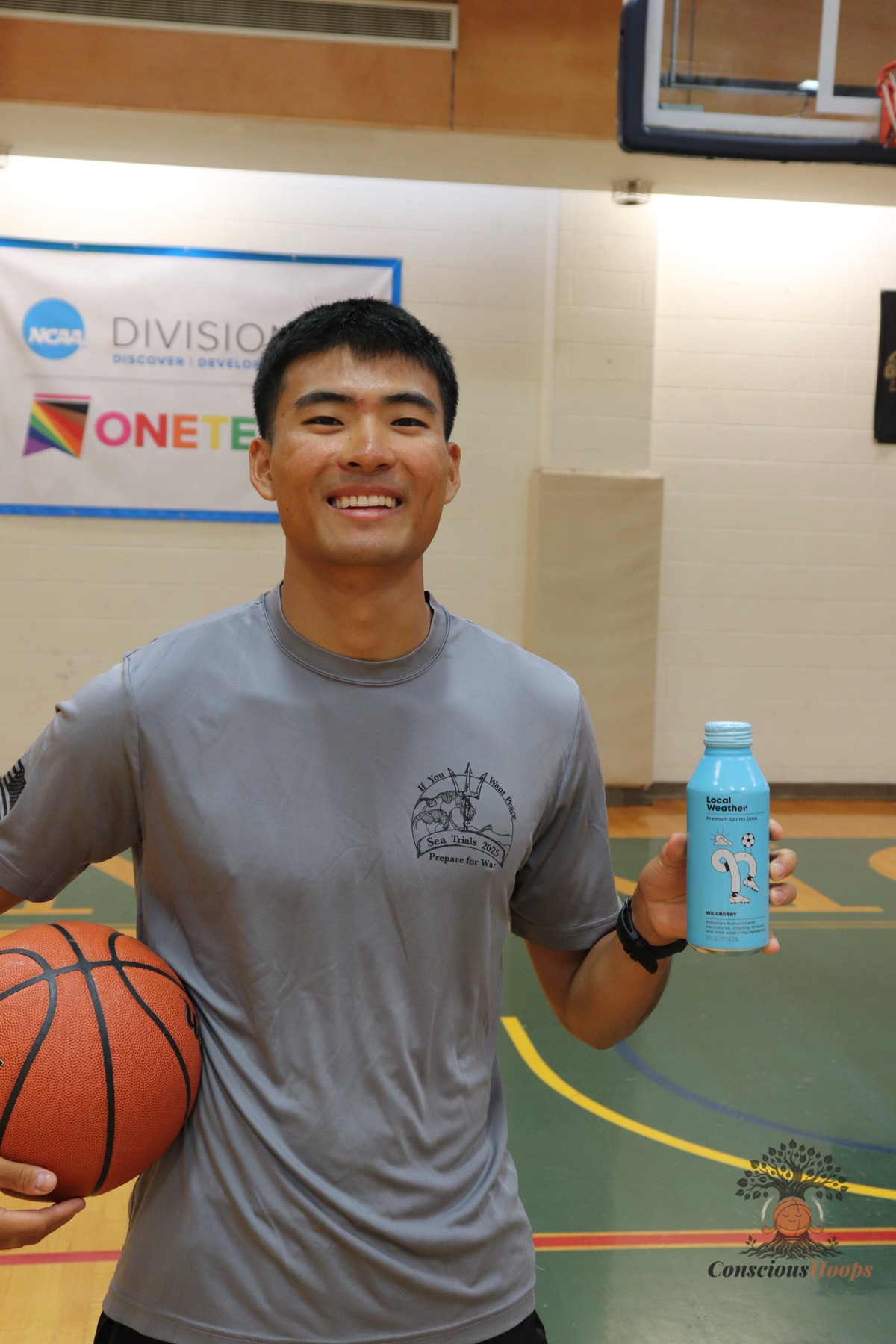 A player smiling with a basketball and a sports drink