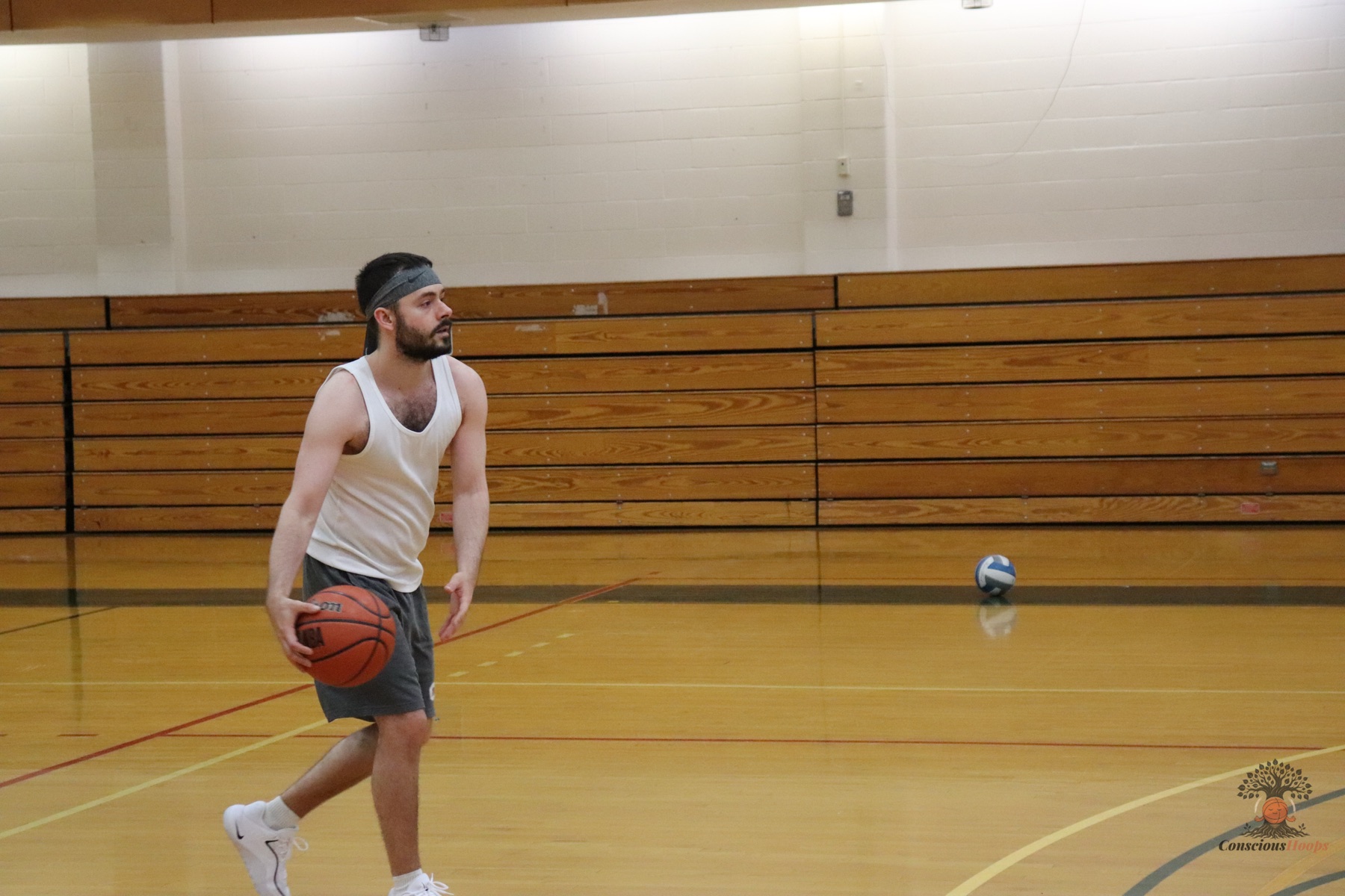 A player in a headband dribbling up the empty court