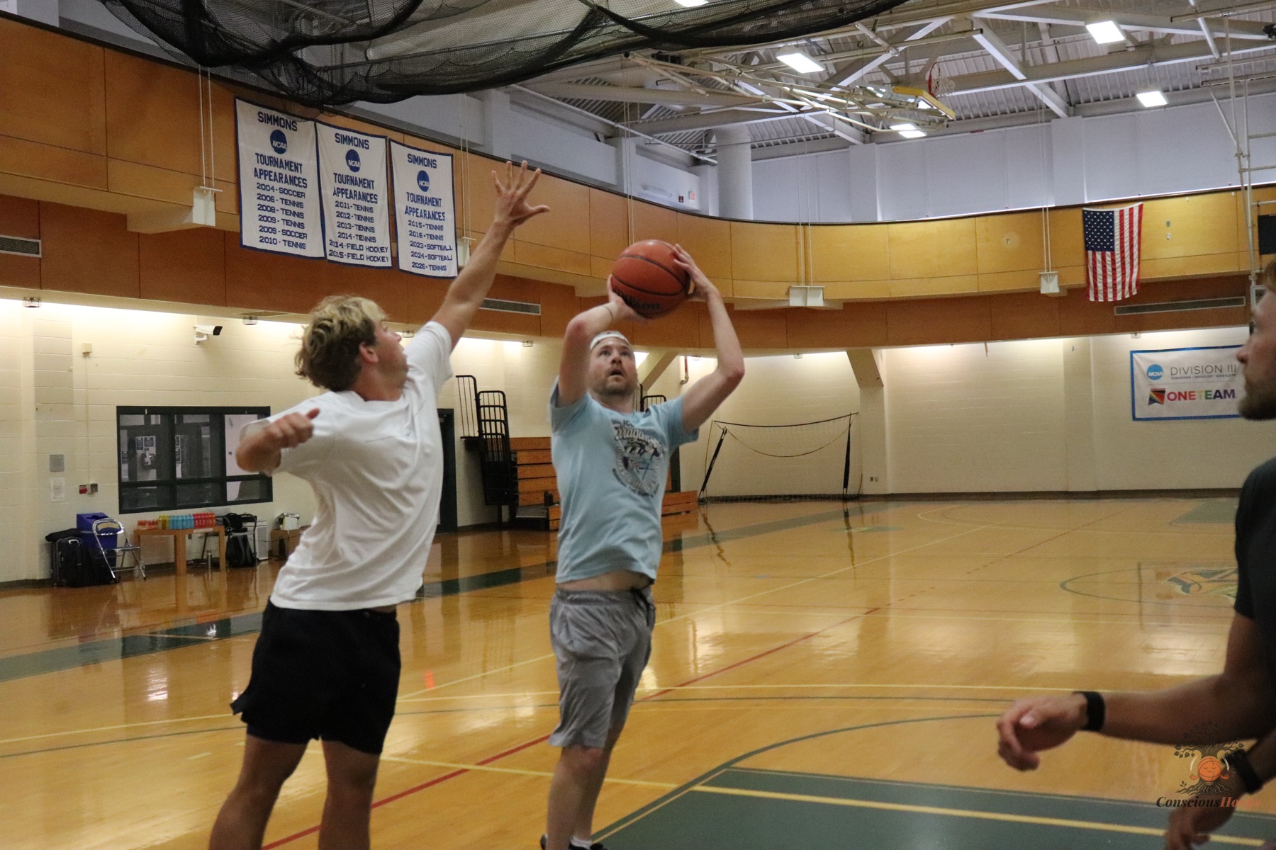 A shooter releasing over a contesting defender under the banners