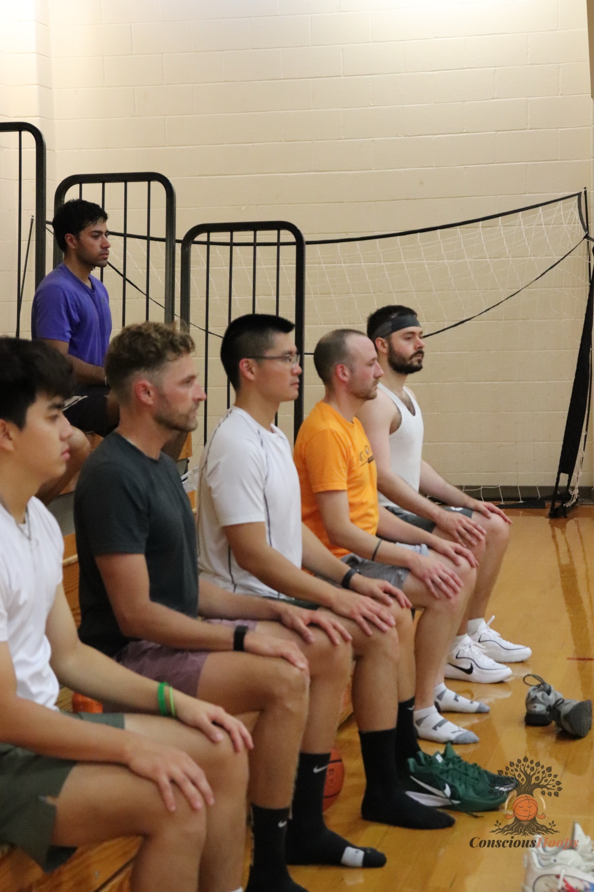 Players sitting courtside in a group meditation after the run